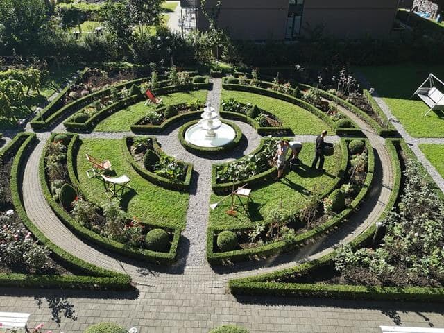 Gepflegter runder Ziergarten mit Buchshecken und Brunnen von oben